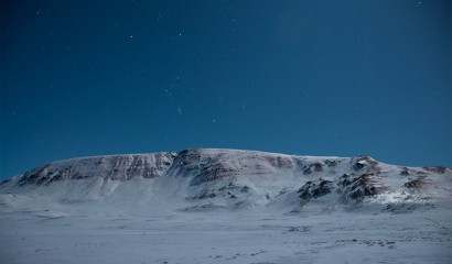 Snöklädda berg endast upplyst av månen en stärnklar natt, Island Snöklädda berg endast upplyst av månen en stärnklar natt, Island