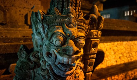 Demon staty i kvällsbelysning längs Sanur strandpromenad, Bali