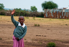 Liten flicka vinkar på oss i Masai by, Kenya