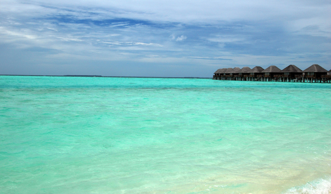 Till höger om vår plats i solen ligger Vilu Reefs watervillas vackert på sina pelare ute i vattnet