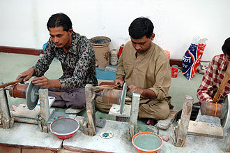 Tre män slipar stenar för hand