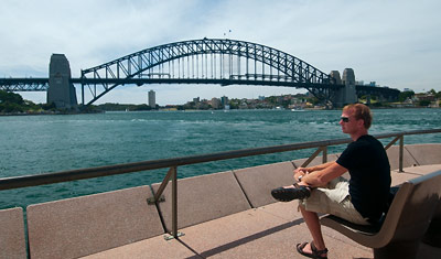 Lasse sitter vid Sydney operahus och blickar ut över Sydney Harbour bridge