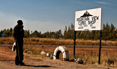 Man funderar över Mountain View Curio Shop skylten utanför Nanyuki, Kenya