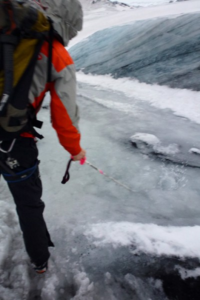 Guiden leder undan smältvatten på glaciären Sólheimajökull, Island