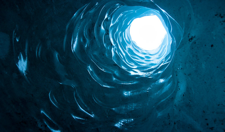 Hål genom glaciären sett underfrån i en isgrotta, Sólheimajökull, Island