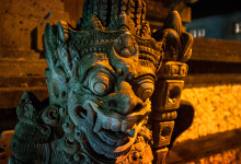 Demon staty i kvällsbelysning längs Sanur strandpromenad, Bali