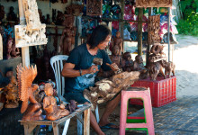 En man täljer träskulptur vid Sanur strandpromenad, Bali