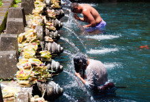 Kvinna ber under heligt vatten från källan vid Pura Tirtha Empul, Bali