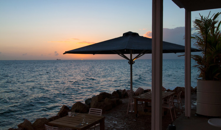 Solnedgång efter att himmeln öppnat upp sig över havet och Bijblauw Hotel i Willemstad