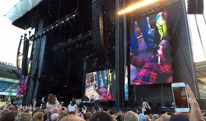 Dave Grohl bärs ut på bår efter att ha fallit av scenen. Han ursäktar och säger de garanterat kommer tillbaka.